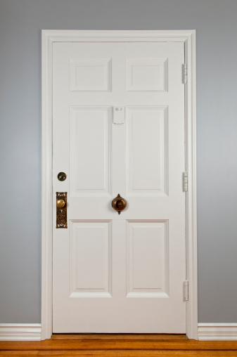 White front door with antique hardware to a traditional house.