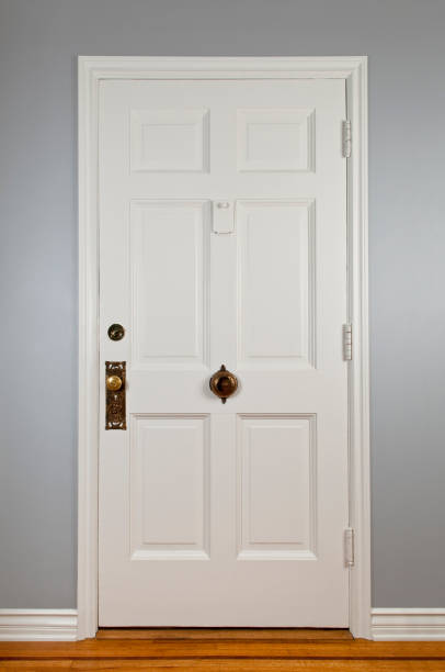 White Front Door White front door with antique hardware to a traditional house. moulding door jamb wood stock pictures, royalty-free photos & images