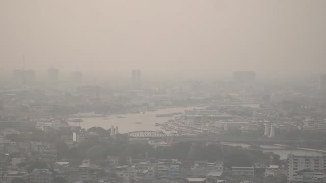 The cityscape of Bangkok is obscured by a thick blanket of dust and pollution