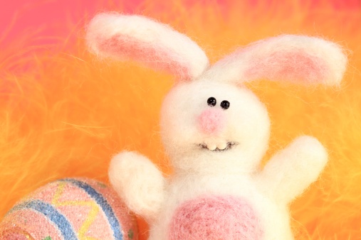 XXXL photo of a stuffed Easter Bunny (made entirely from scratch by the photographer) with a very short depth of field with focus on his eyes so the feather yellow background, and edges are blurred and soft and fuzzy looking.   Macro - ..giving the texture of the fuzzy fur the look of a retro animation character.