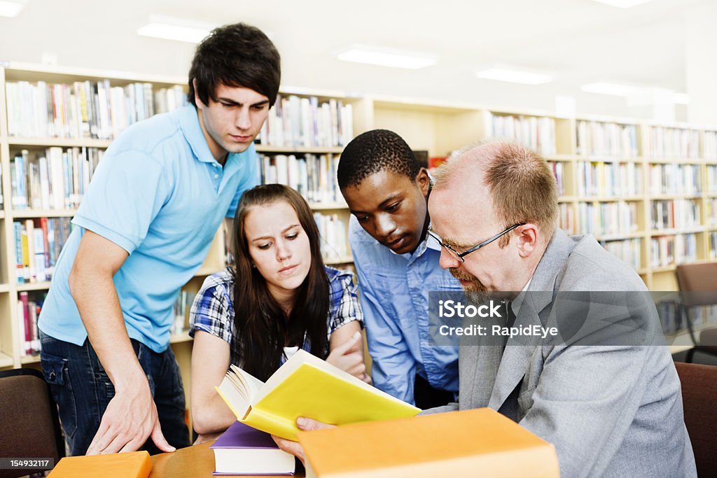 Tre studenti e insegnante di lavorare insieme nella Libreria - Foto stock royalty-free di Adulto