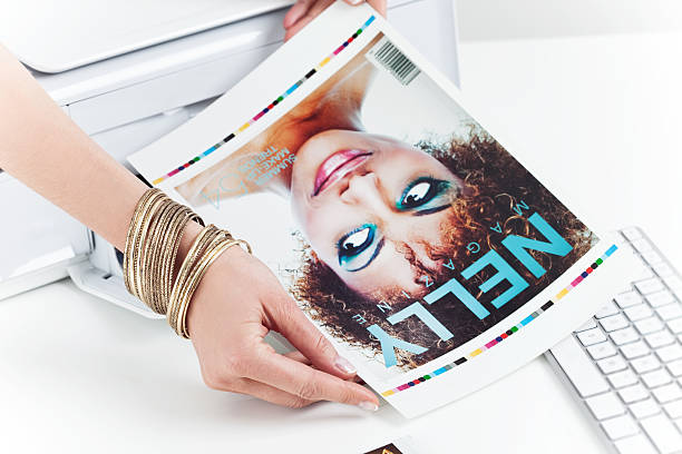 Photo editor at work Female hand taking printout of the cover of Beauty/Fashion Magazine from printer.  printout photos stock pictures, royalty-free photos & images