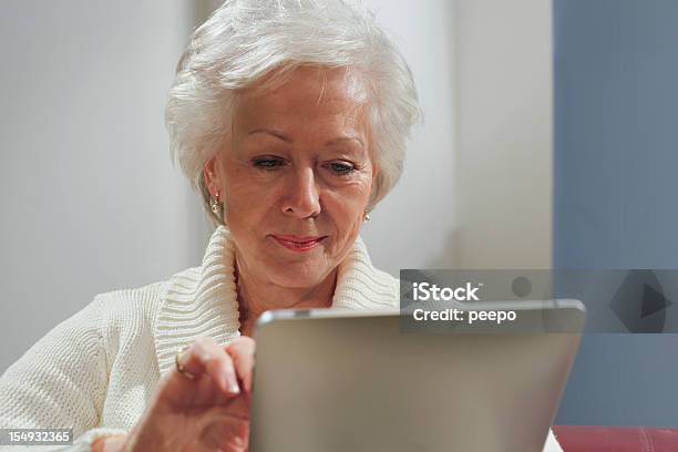 Mujer Senior Usando Tableta Foto de stock y más banco de imágenes de Adulto - Adulto, Adulto maduro, Agarrar