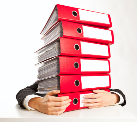 red ring binders against a white background; A bored businesswoman sitting behind a stack of file folders on the table.