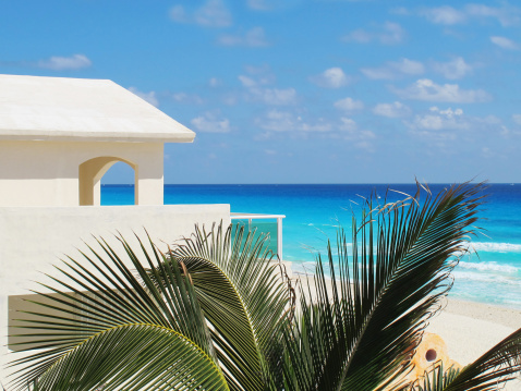 People swimming near white sand beach with umbrellas, bungalow bar and cocos palms, turquoise caribbean sea, Isla Mujeres island, Caribbean Sea, Cancun, Yucatan, Mexico.