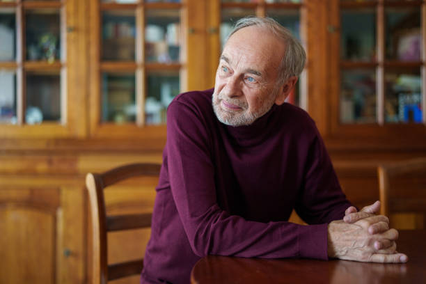 istock Senior man sitting at dining table with clasped hands 1549330638