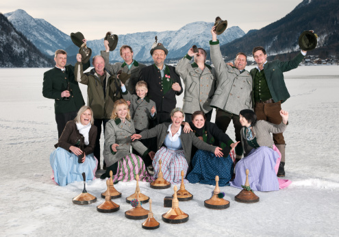 Funny group shot of an Austrian Curling Team in traditional Tracht on the frozen Lake Grundlsee in front of a stunning Alps Panorama. Great Dynamic and funny expressions. Nikon D3X. Converted from RAW.