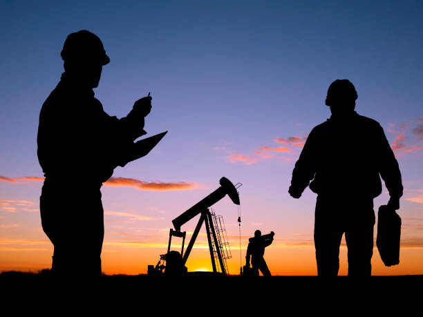 Três trabalhadores fazer negócios no poço de petróleo Pumpjack - foto de acervo