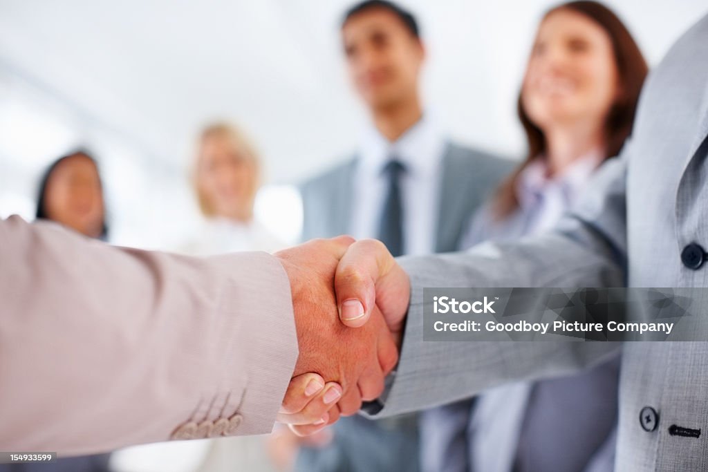 Uomini d'affari si stringono la mano dopo un affare - Foto stock royalty-free di Persone d'affari
