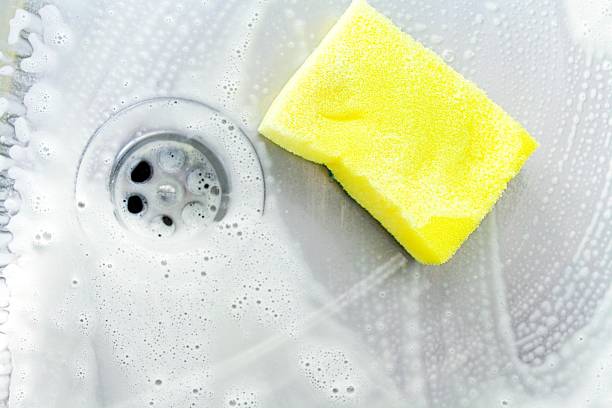 cleaning a sink with yellow sponge cleaning a sink with yellow sponge and cream cleanser bath sponge photos stock pictures, royalty-free photos & images