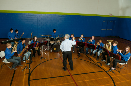 A highschool band performing in a gym.