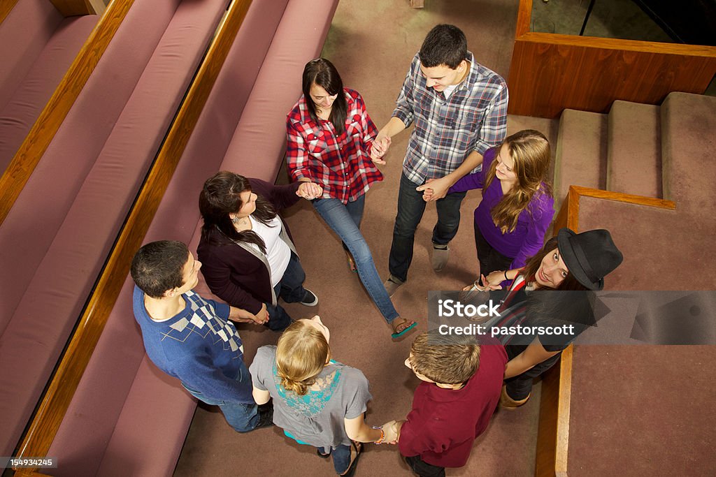 Church Youth Group Circle Circle of friends supports one another holding hands and laughing at church with one looking up with smiling face Circle Stock Photo
