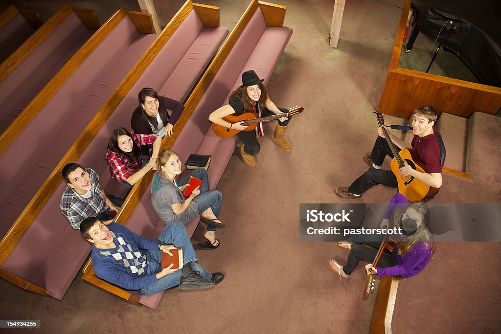 Happy Church Musical Youth Group Eight teen friends play guitar and worship together in church setting as seen from high angle view Church Stock Photo