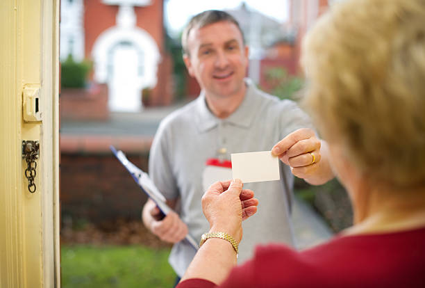 travelling salesman official or bogus caller shows senior lady his card , left blank for your own info to be added door to door salesperson photos stock pictures, royalty-free photos & images
