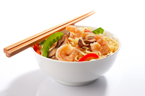 A bowl of stir-fried Asian noodles with prawns and chopsticks.