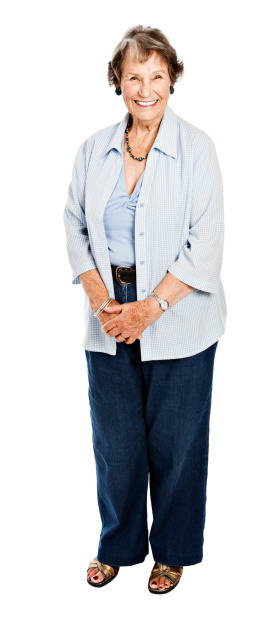 This senior woman gives a beaming smile as she stands, hands clasped, against a white background. 