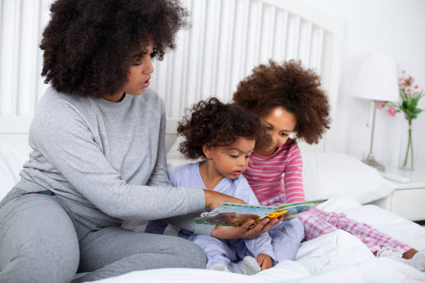 istock Mother with daughters reading books in bed 1549355000