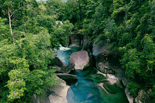 Aerial view of Babinda Boulders North Queensland, Australia,  beautiful rainforest creek running through boulders, blue and green rainforest creek, blue water  running through large boulders, dangerous rainforest creek and large boulders, rainforest creek with swimming platform, with drone point of view,