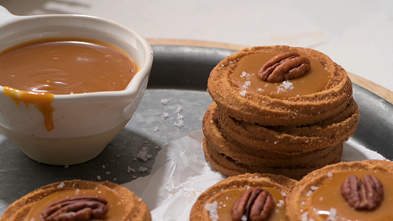 Caramel cookies with pecan nuts served on roud plates, in the kitchen after baking.