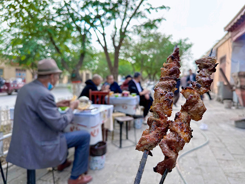Kuqa，XINJIANG / China -april 21 2023:The commercial street in the old city of Kuqa, Xinjiang,People eat local food in restaurant