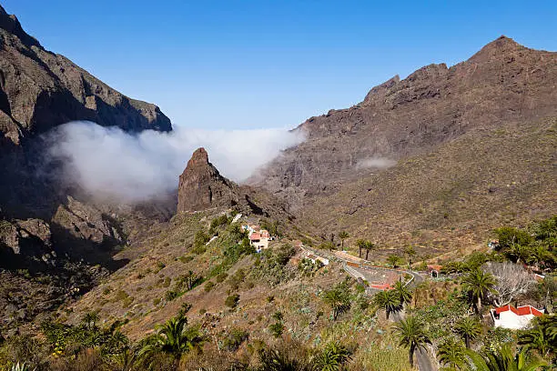 Masca is a small mountain village located in the Teno mountains, northwest of Tenerife. Until the 1960s the village was accessible only by paths, but today a small winding road reaches it among a beautiful mountain scenery. In the village you find only a small square, a church and some bars. But this is one of the most visited sites of Tenerife, thanks to its idyllic landscapes. From here starts the footpath that goes down through the Barranco de Masca, a long ravine that ends to the sea. It is a very spectacular but challenging course, especially if it faces downhill and uphill. That's why many tourists come this far by bus or taxi, then walk down through the Barranco to the sea and then take the ferry to Los Gigantes. Tenerife, Canary Islands. 