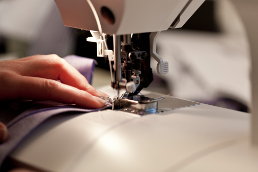 Closep up tailor process, women's hand working on sewing machine sew denim fabric