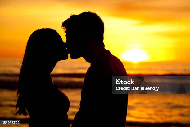 Silhoueted Casal A Beijar Ao Pôr Do Sol - Fotografias de stock e mais imagens de 20-29 Anos - 20-29 Anos, Adulto, Adulto de idade mediana