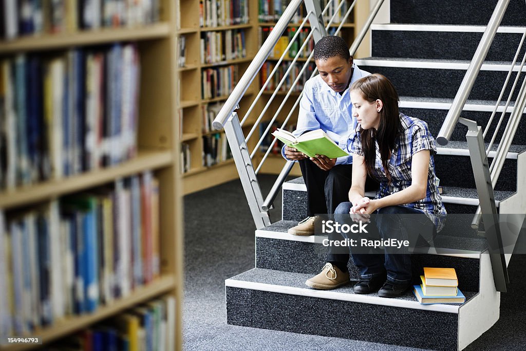 Zwei Studenten sitzen auf Schritte Sie ein Buch in der Bibliothek - Lizenzfrei Afrikanischer Abstammung Stock-Foto