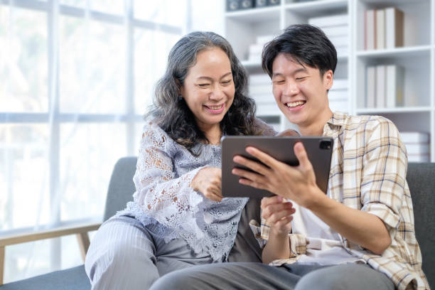 istock Smiling young man with elderly mother using digital tablet at home. People, technology and family. 1549469508
