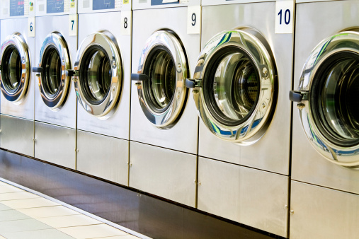 A close-up caption from a diagonal view of metallic lustered clothes washer’s in a public launderette. Horizontal shot, image taken with a full frame camera and a prime lens at daylight.