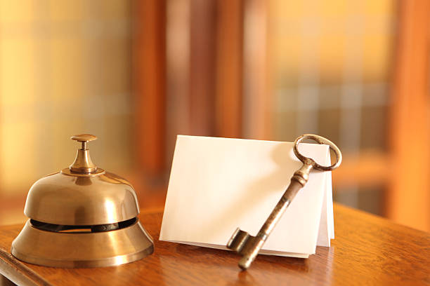 Service bell, old fashioned door key and card in hotel lobby stock photo