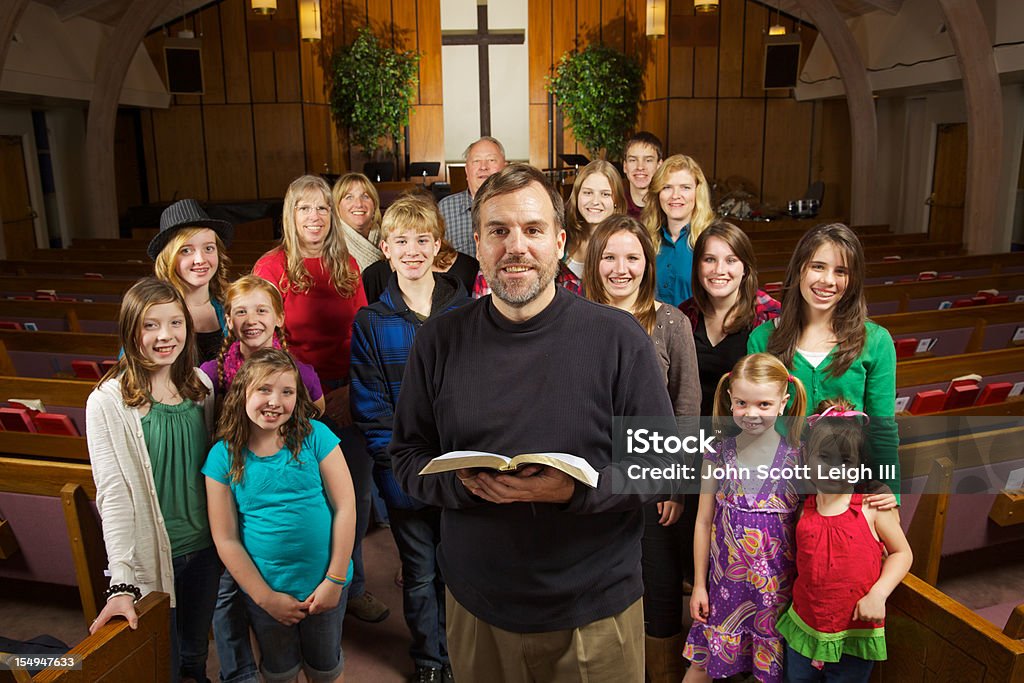 Friendly Smiling Church Indoors Group Pastor A friendly,happy church with their pastor smiling and facing the camera while inside a traditional church sanctuary and cross on wall in background,cross,pews,indoors,group,large group of people,group shot,facing camera,expressing positivity, multi generational,men and women, boys and girls, cross in background,copy space Congregation Stock Photo