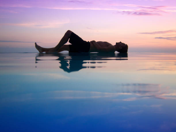 istock Silhouette of Man Lying Across Sunset Infinity Pool 154947807