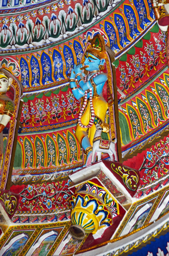 Brilliantly painted Krishna adorning the inner dome of the Sita Ram Ji Temple, Choti Chopar, Jaipur, Rajasthan, India. Playing flute and cow at his feet.