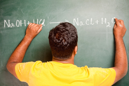 One Ambidextrous Indian Man writing Chemical Equation on Greenboard with both the hands