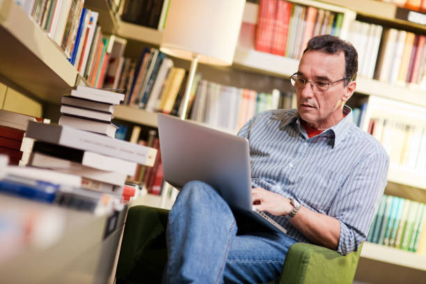 istock Mature adult  man using laptop in library 154948645