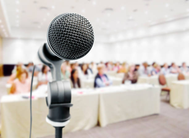 istock Closeup of microphone against blurry auditorum 154948659