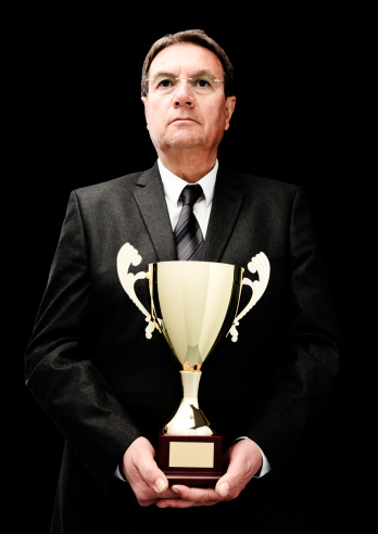businessman holding golden cup on black background