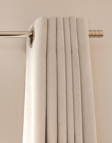 a view of the top of a closed set of light grey silk curtains on a modern chrome curtain rail. 