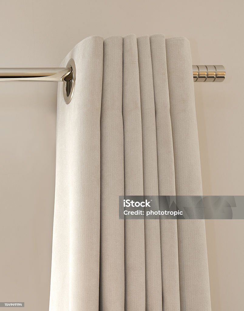 silk curtains a view of the top of a closed set of light grey silk curtains on a modern chrome curtain rail.  Curtain Rail Stock Photo