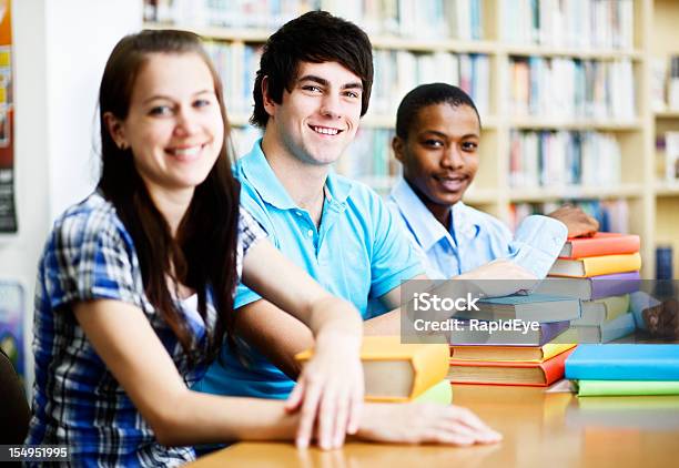 Três Bom Olhar Sorridente Estudantes Partilhar Uma Biblioteca Mesa - Fotografias de stock e mais imagens de 20-29 Anos