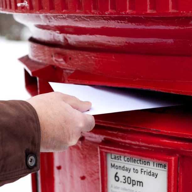 istock Man's hand posting letter in British postbox on snowy day 154952183