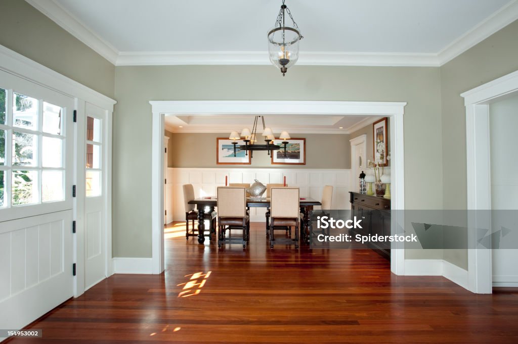 Front Entrance And Dining Room Looking into dining room through the front entrance of a traditional home. Baseboard Stock Photo