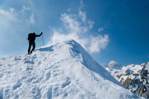 Rear view of male climber reaching the mountain peak in winter time,  Julian Alps, Slovenia, Europe