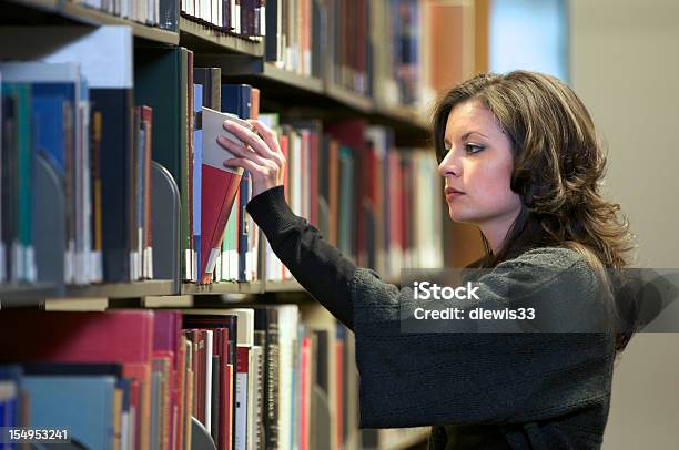 Bastante Joven Seleccionando Un Libro En La Biblioteca Foto de stock y más banco de imágenes de 20 a 29 años