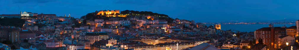 The landmarks of Lisbon illuminated by the warm glow of street lights under deep blue dusk skies. ProPhoto RGB profile for maximum color fidelity and gamut.
