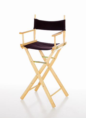 A black director's chair on a white reflective floor.