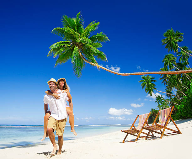 istock Young couple on a tropical beach with lounge chairs 154954249