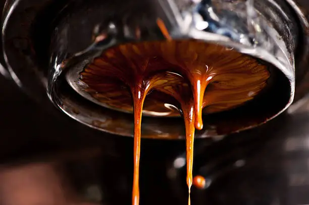 Coffee machine pouring out a cappaccino into coffee mugs