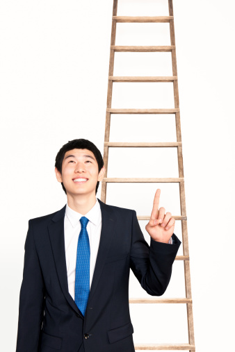 Asian businessman pointing up a ladder